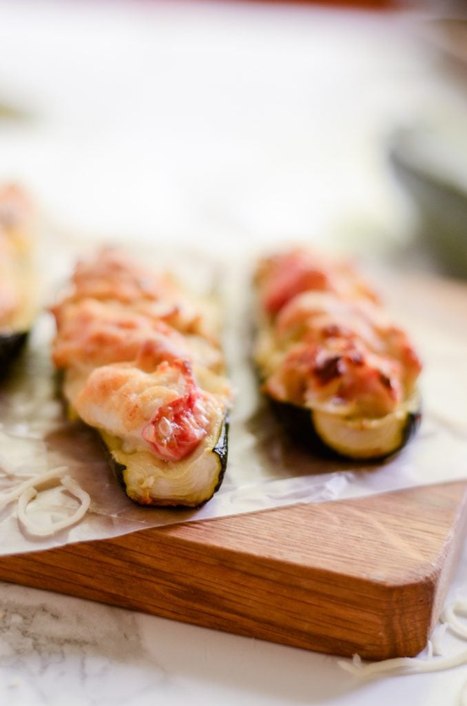 Close up of crab and artichoke stuffed zucchini on wax paper and wooden cutting board