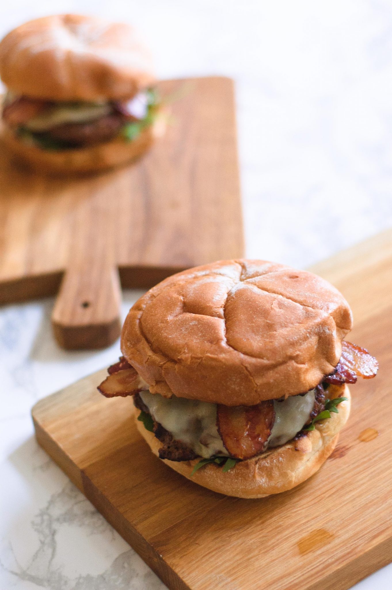 Two caramelized onion burgers on wooden cutting boards.