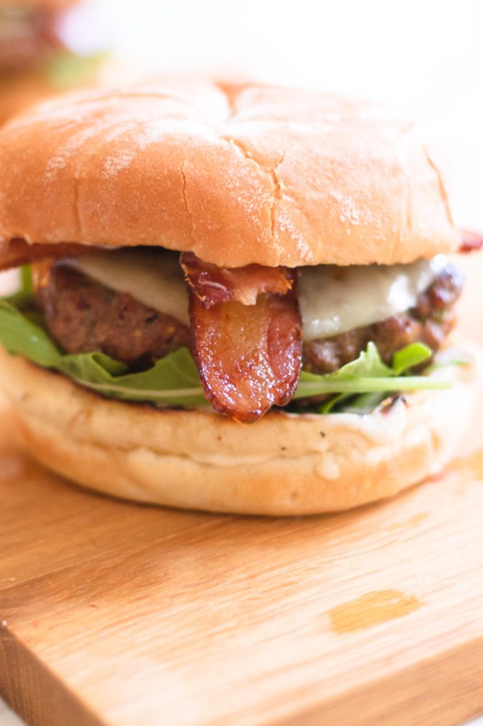 a caramelized onion burger with bacon sticking out of it.