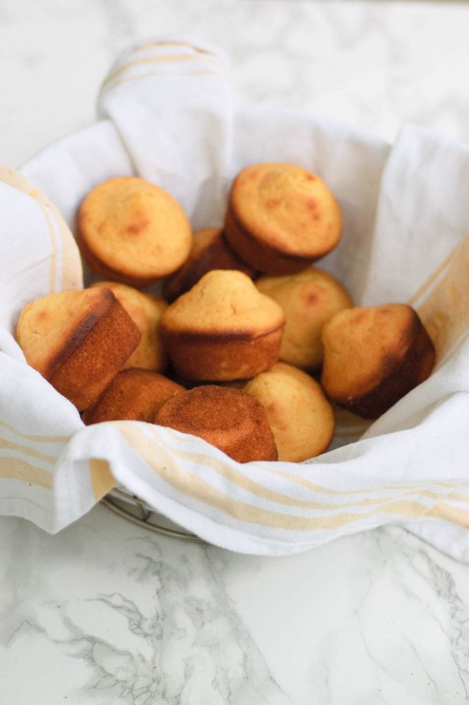 A towel lined basket of corn muffins.