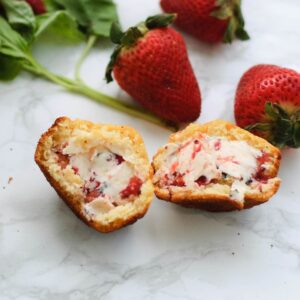 A basket of honey corn muffins surrounded by basil and strawberries