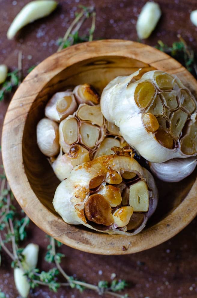 overhead shot of a wooden bowl with roasted garlic