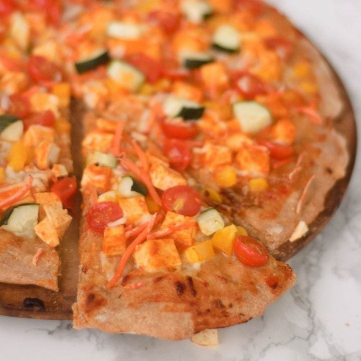 a slice of curry pizza being removed from the whole pizza.