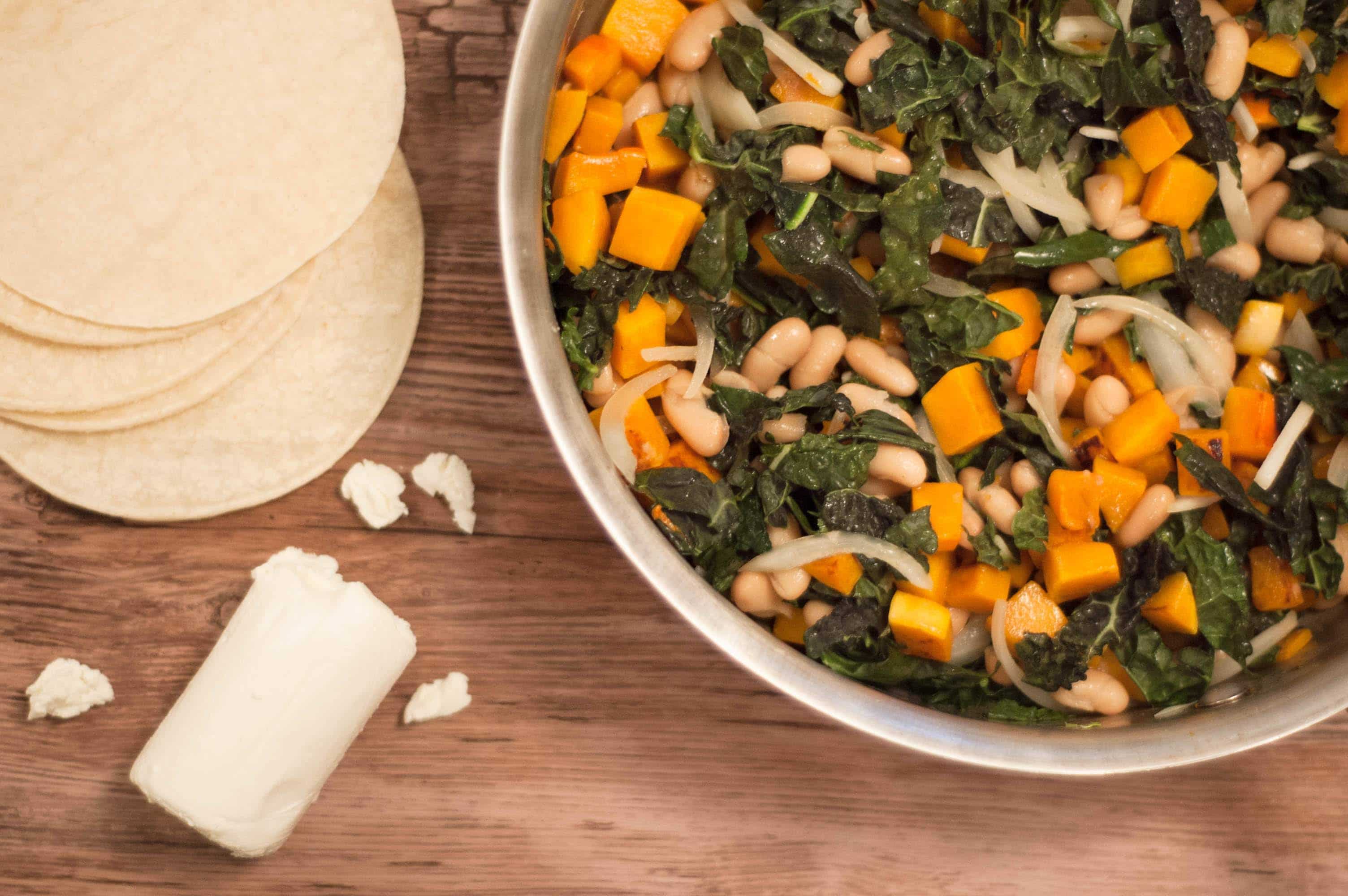 pan of pumpkin taco filling next to corn tortillas and goat cheese