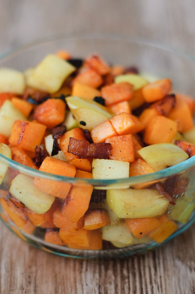 A bowl of harvest toppings, including bacon, green apple, and pumpkin.