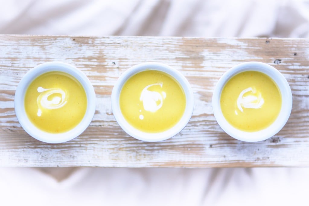 Three bowls of yellow purée on a white board.