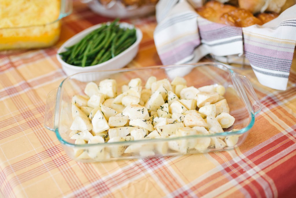 A thanksgiving table with roasted parsnips in a baking dish.