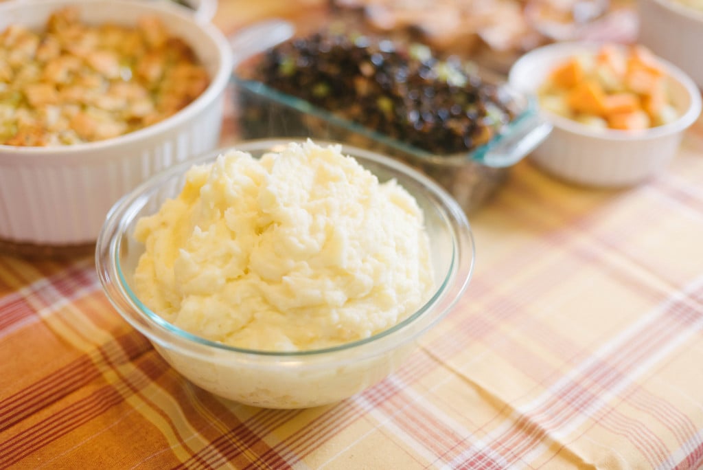 Close up of a bowl of mashed potatoes on a Thanksgiving table.