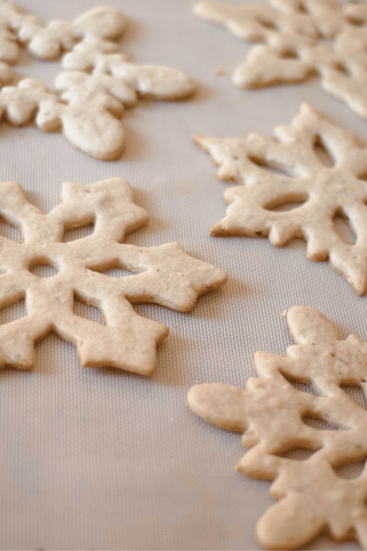 Three different shapes of almond sugar cookie next to each other on a silicone baking mat.