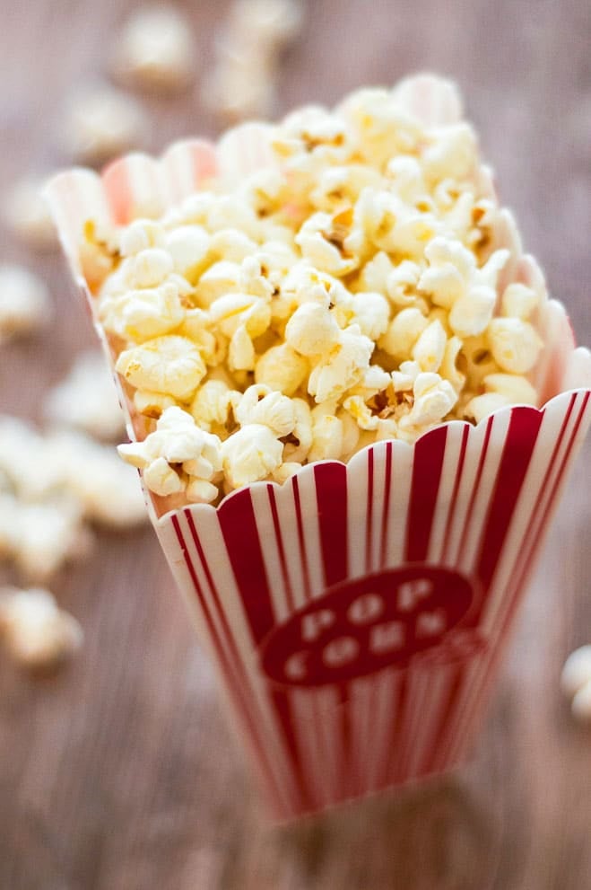 A red striped plastic popcorn container filled with stovetop popcorn