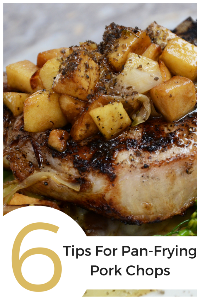 A pan fried pork chop with chopped apples on top.