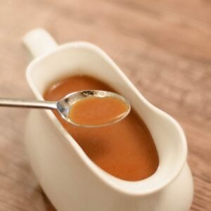 a spoonful of espagnole sauce being removed from a gravy boat.