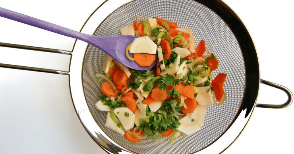 A mesh strainer with ingredients strained out from making stock.