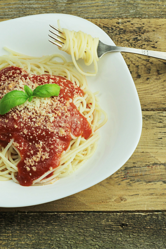 A fork spinning pasta off of a plate.