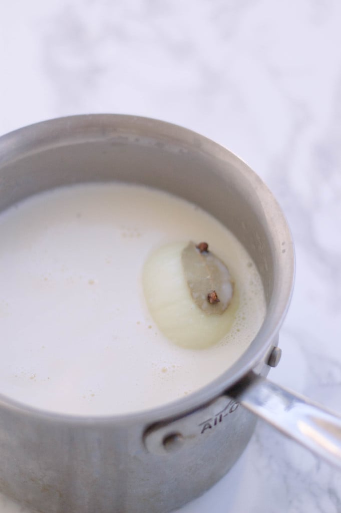 An onion pique floating in a pot of milk.
