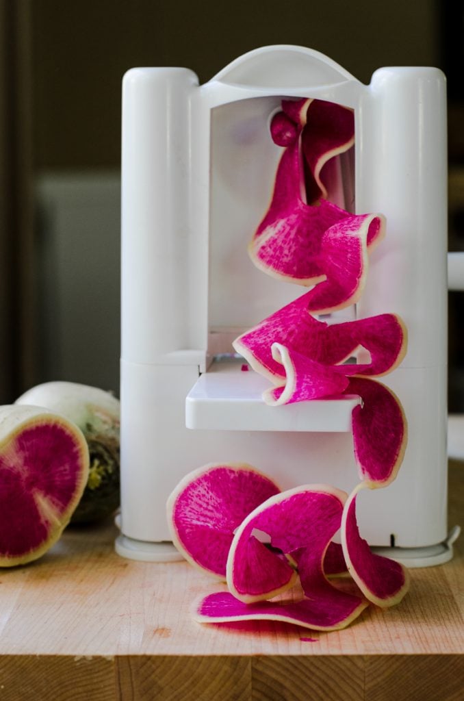 A spriralizer cutting a watermelon radish into ribbons.