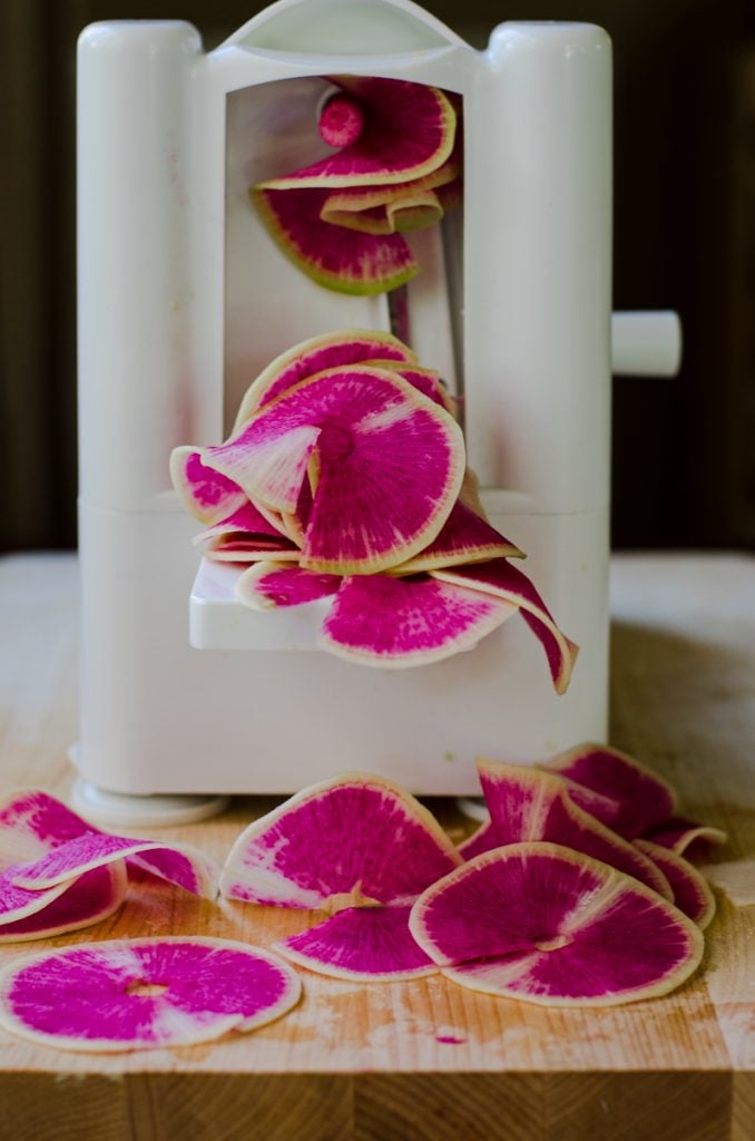 A spiralizer cutting watermelon radish into rounds.