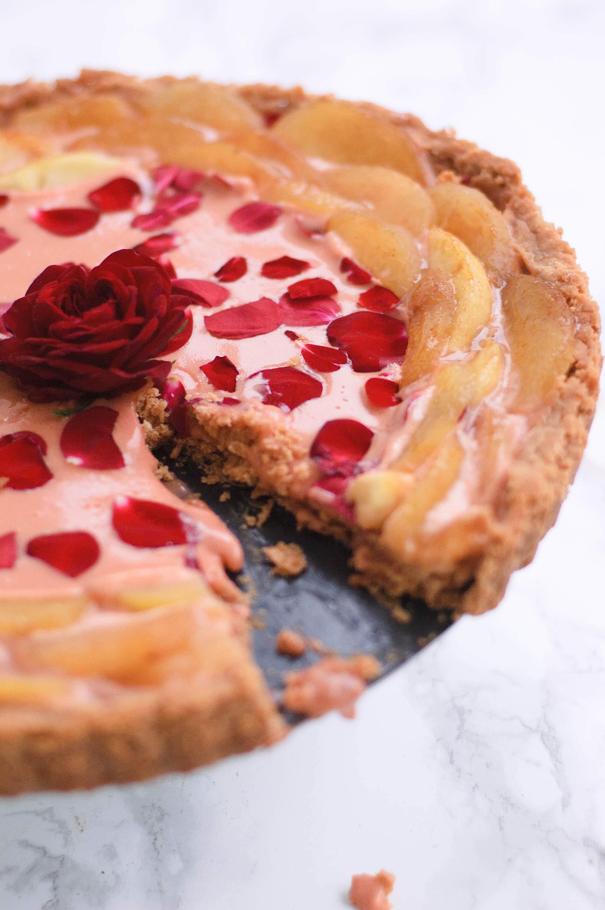 the rose curd and white peach tart with a piece missing from it.  It has an edible rose in the middle.