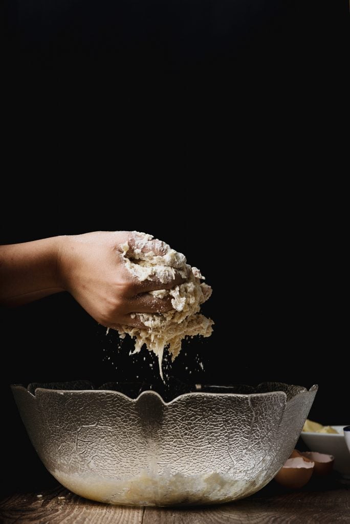Hands mixing dough over a clear bowl