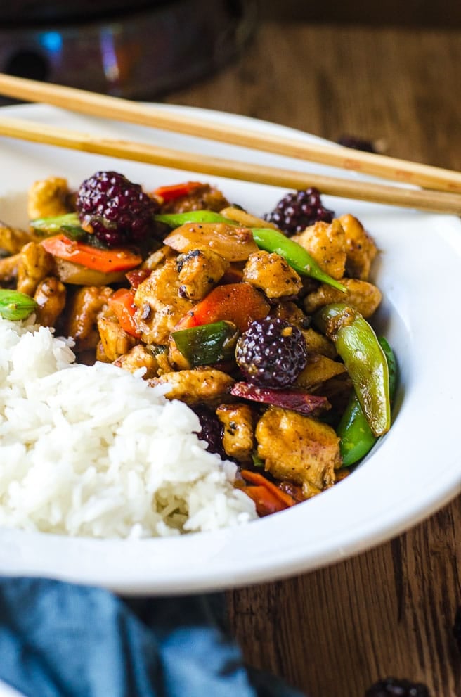 A white bowl with stir fry in one half and white rice in the other.