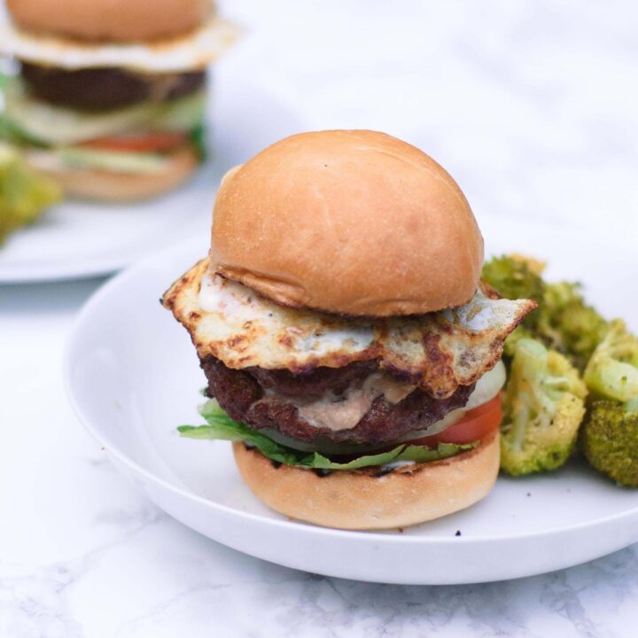 Close up view of a boursin stuffed breakfast burger on a white plate