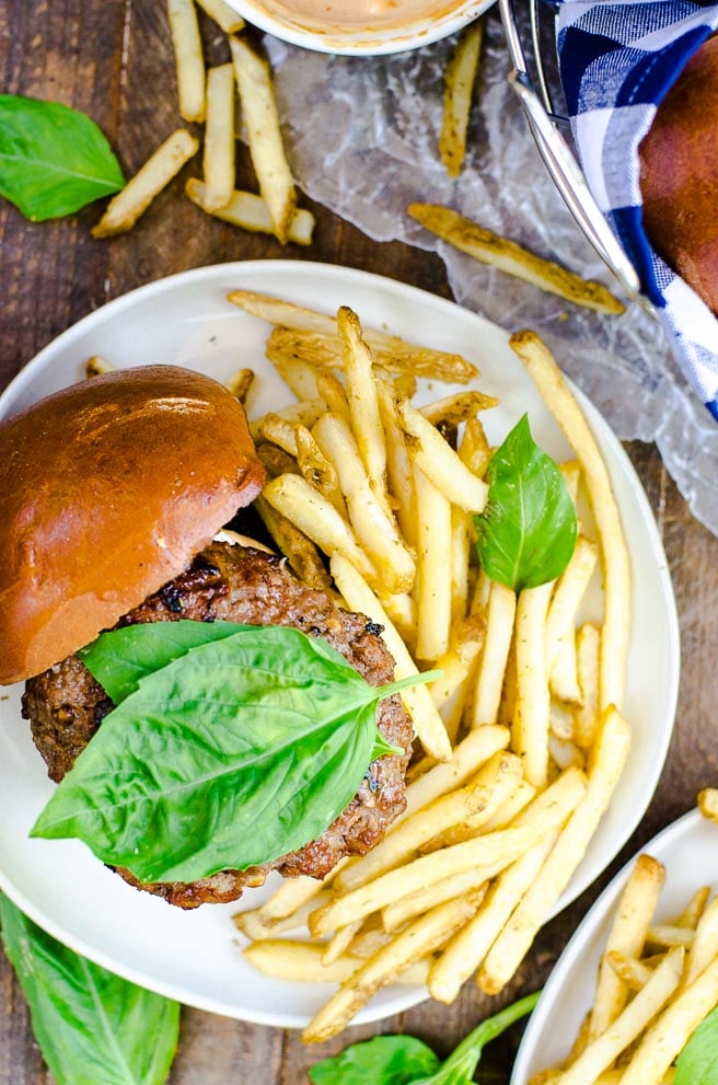 Overhead view of an open face burger next to french fries.