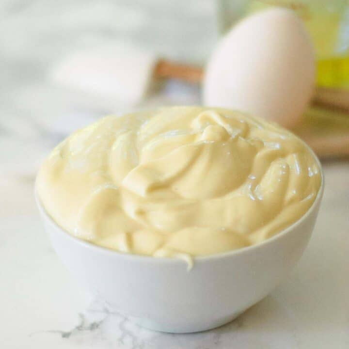 A bowl of homemade mayonnaise in front of the ingredients for making it.