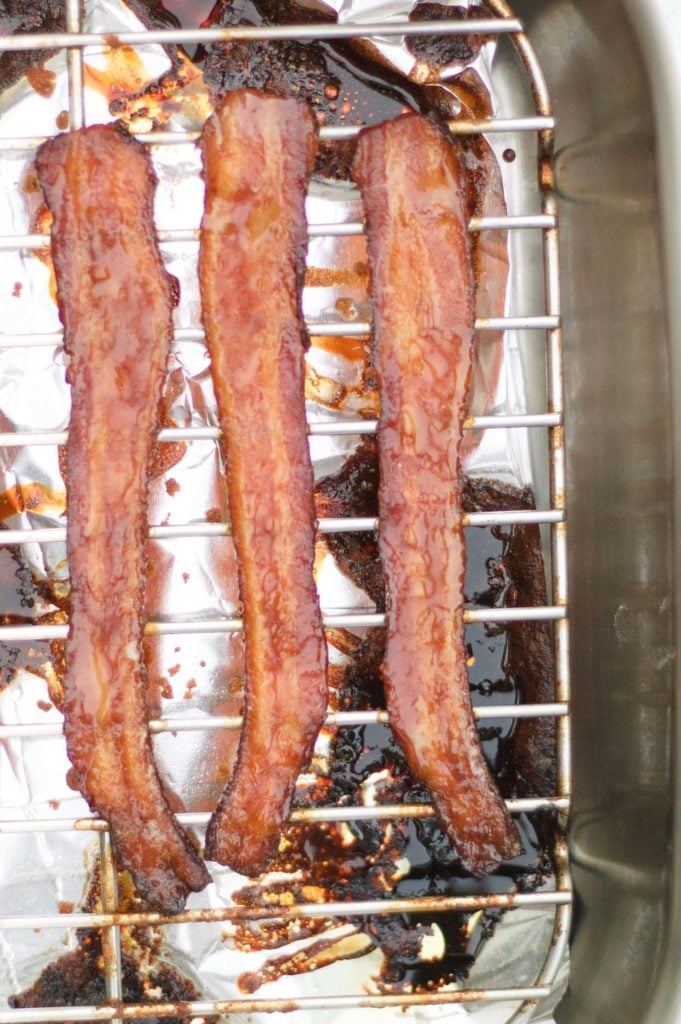 three strips of cooked teriyaki bacon on a roasting pan
