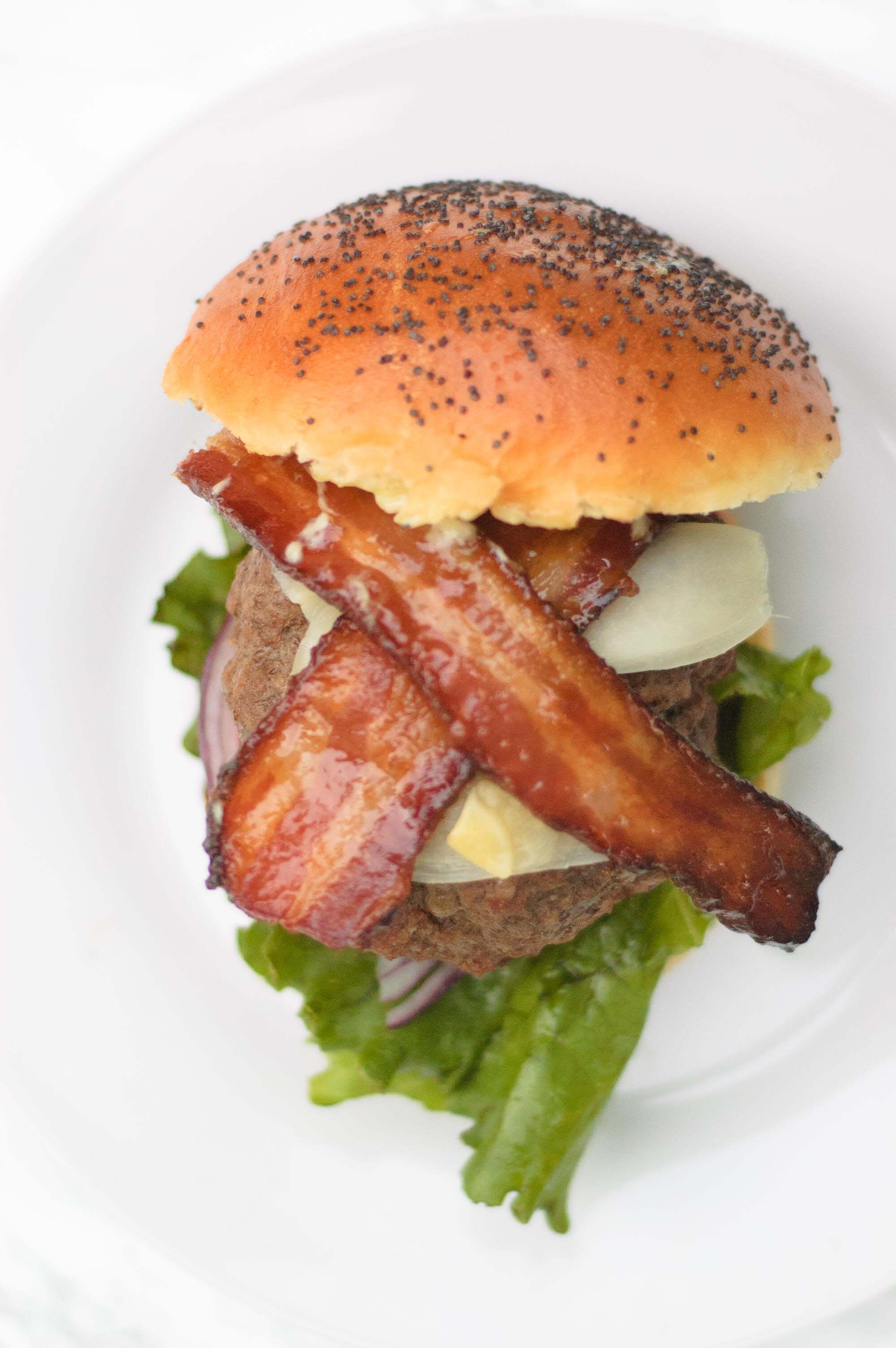 overhead view of the wasabi burger. The bacon is crisscrossed and the bun is on the side.