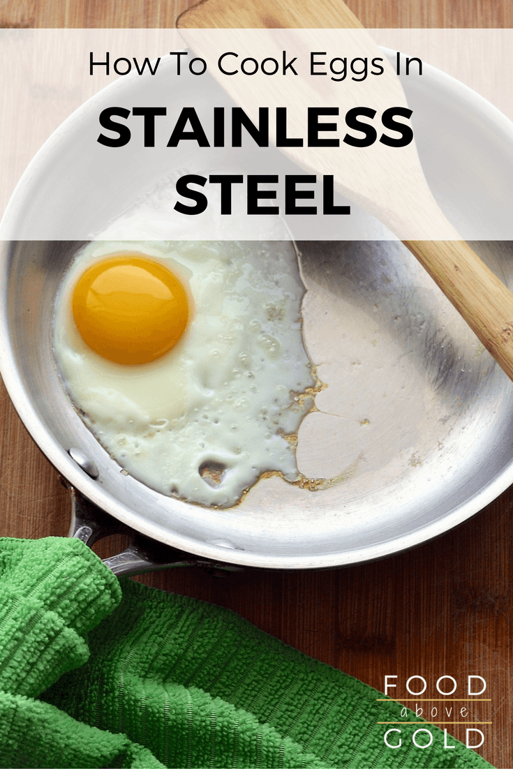 A stainless steel pan cooking an egg with a wooden spatula.