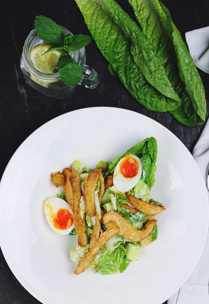 overhead view of a white plate with a salad and soft boiled egg yolks.