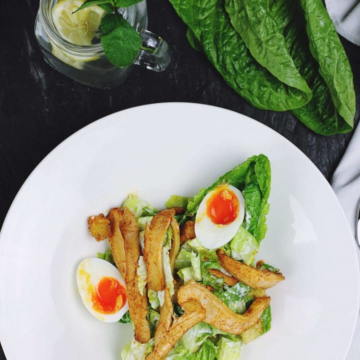 overhead view of a white plate with a salad and soft boiled egg yolks.