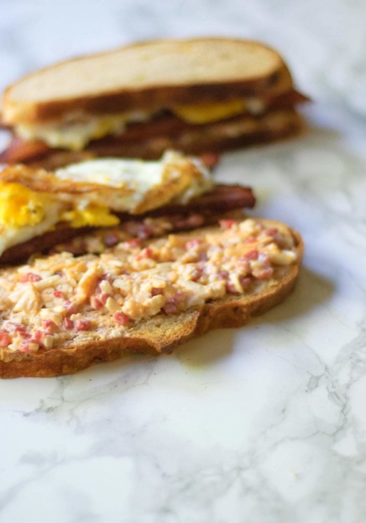 An open faced fried egg sandwich smeared with pimento cheese.