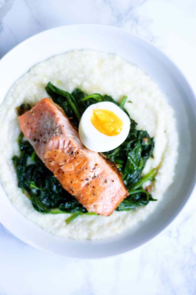 overhead image of salmon and grits in a white bowl