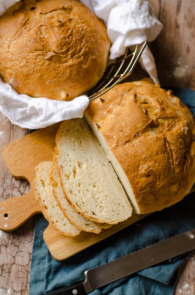 Overhead view of a partially sliced loaf of apple olive oil bread on a cutting board.