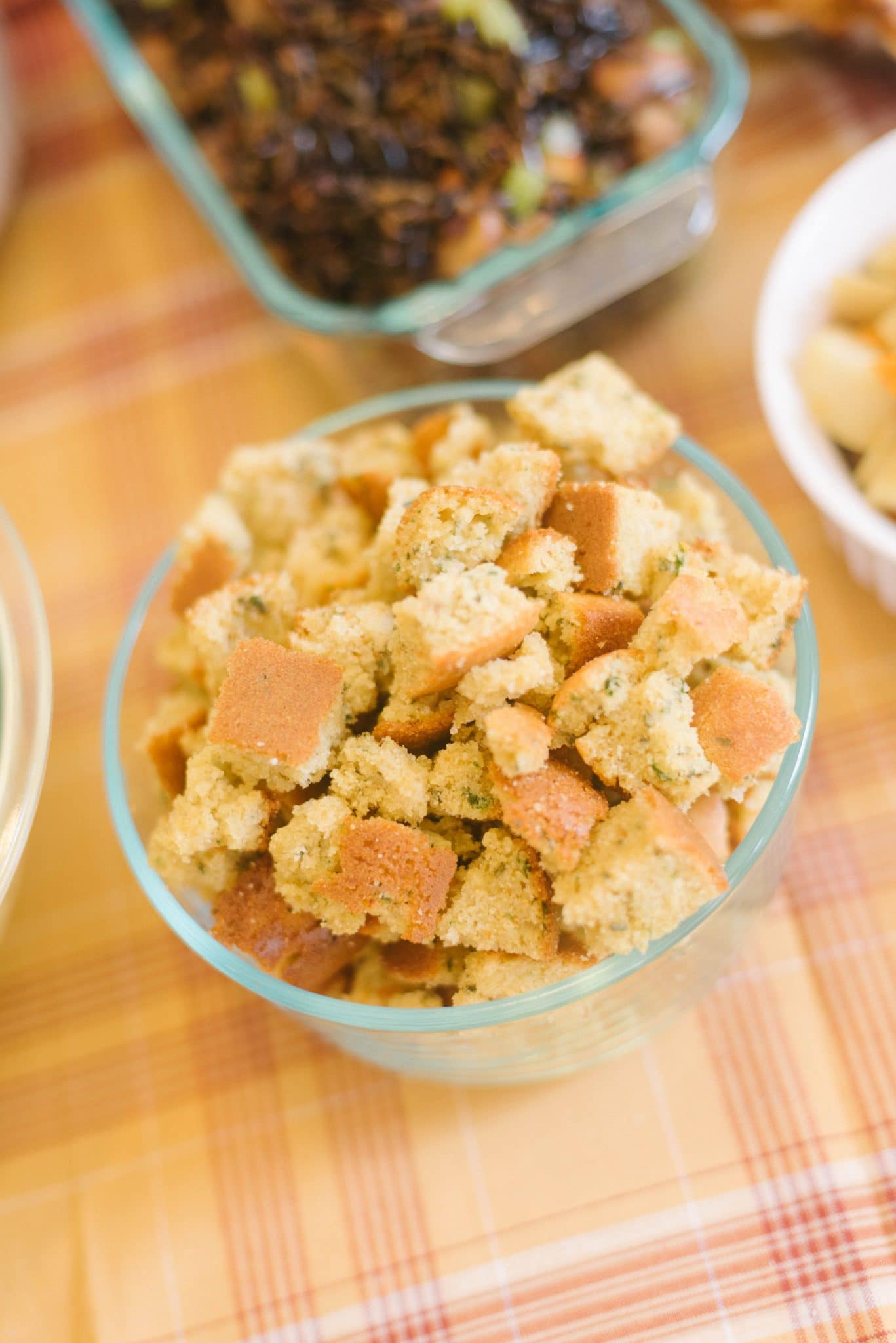 A clear bowl filled with herbed cornbread pieces before becoming stuffing.