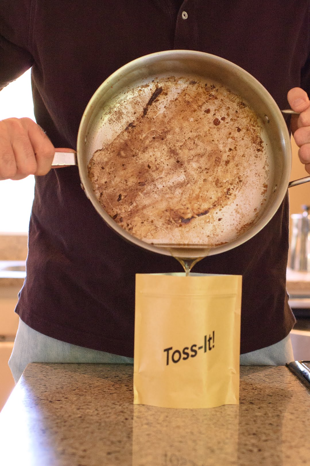 Someone pouring a skillet of grease into a disposal container.