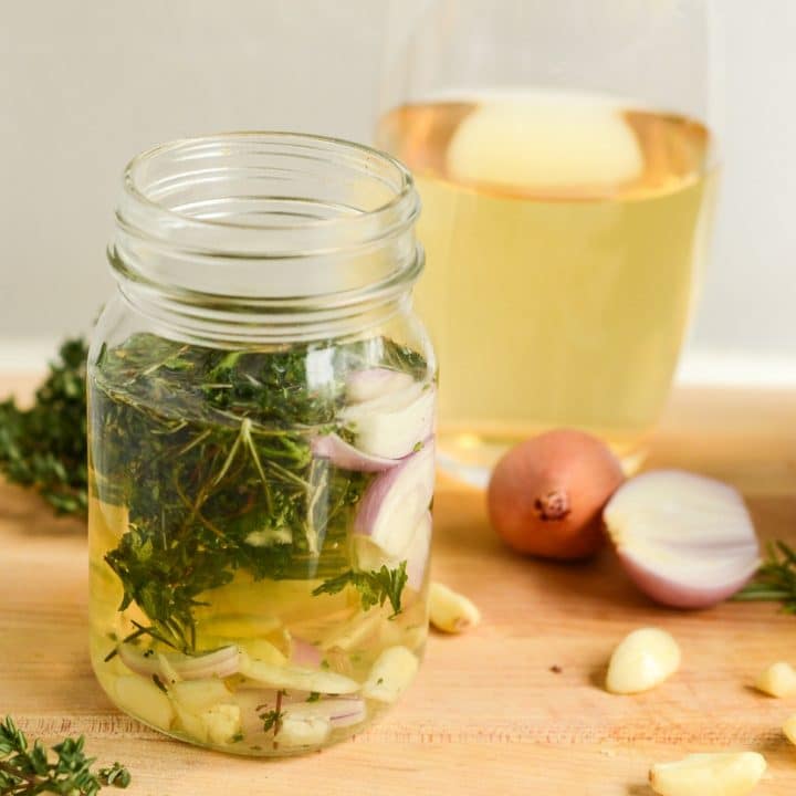 a mason jar of white wine and fresh herbs marinade next to ingredients