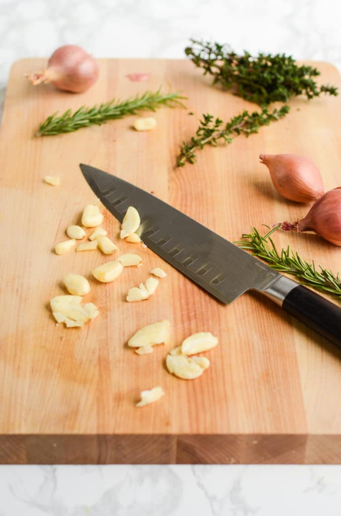 A knife cutting aromatics for a grilled vegetables marinade.