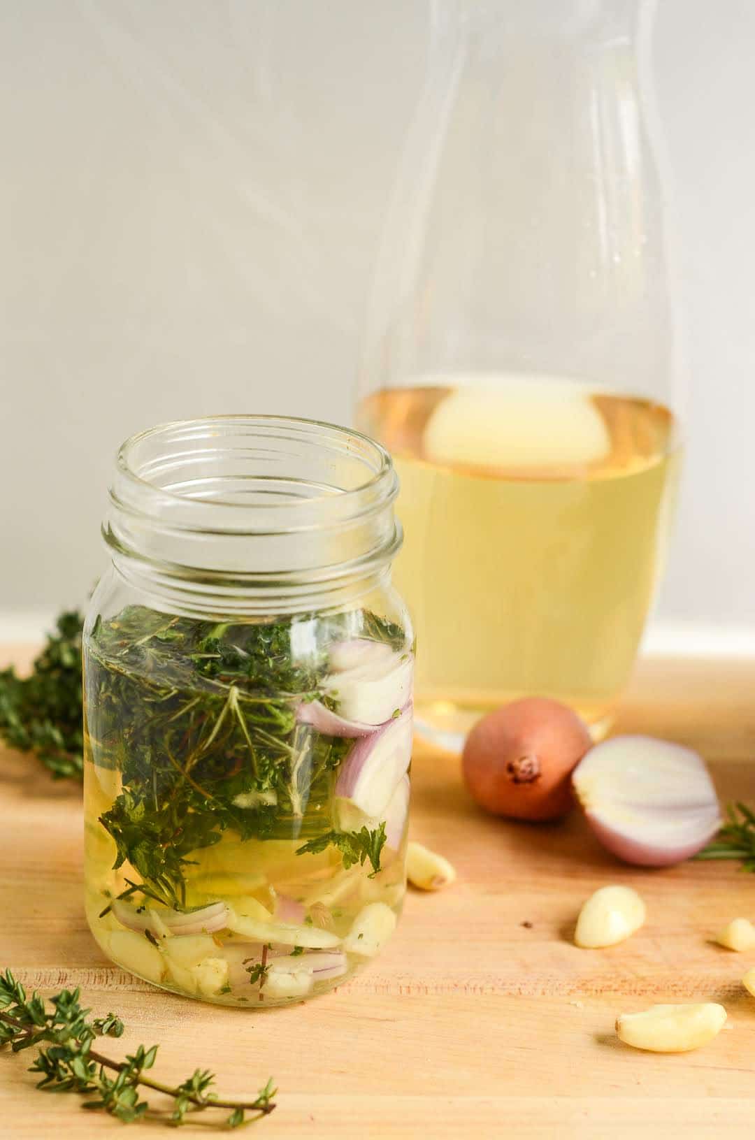 carafe of white wine behind mason jar of White Wine and Fresh Herbs Marinade