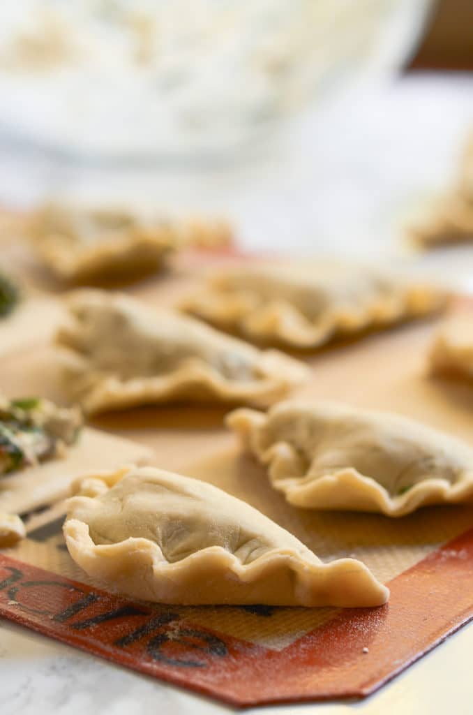 Close up of uncooked mini hand pies with crimped edges on silicone mat