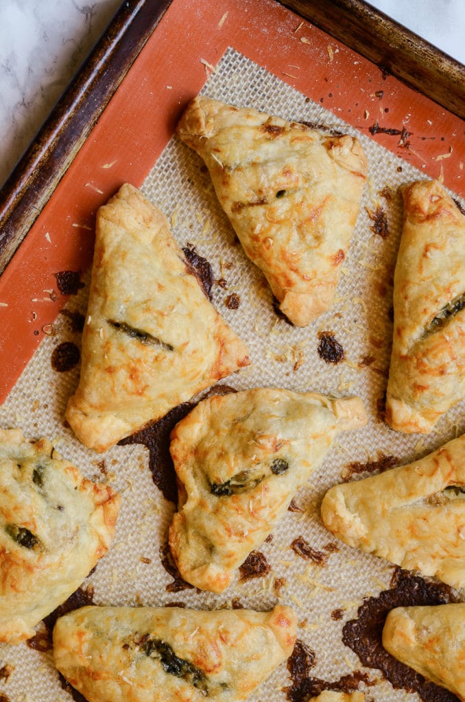 Cooked mini chicken, bacon, spinach, artichoke hand pies on sheet pan
