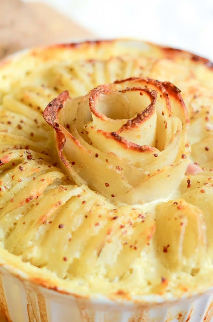 Closeup image of cooked ham and swiss au gratin with crispy potato rose in white corningware