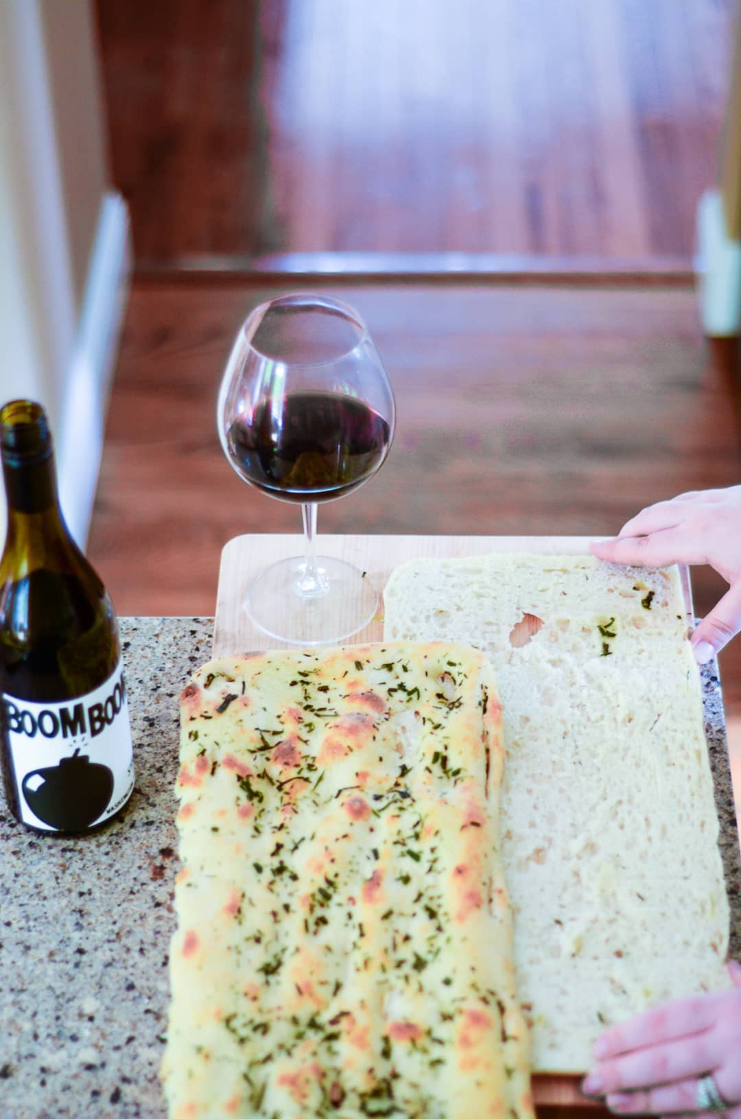 Hands making gourmet grilled cheese next to a glass of wine.