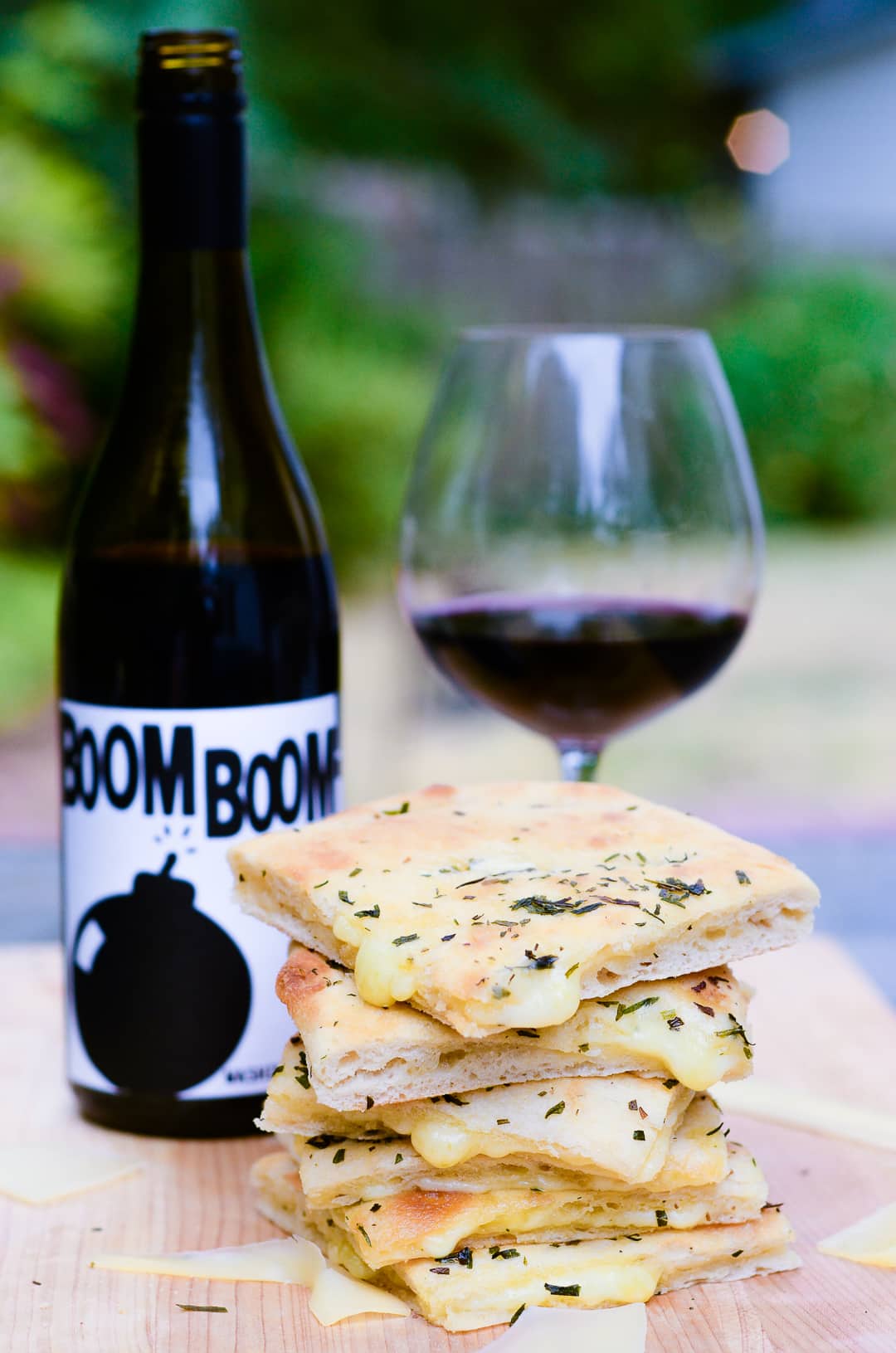 Boom Boom wine bottle and glass behind a stack of gourmet grilled cheese.