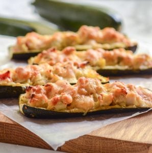 side view of four crab and artichoke stuffed zucchini on wax paper