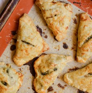 Cooked mini hand pies arranged on a baking sheet.