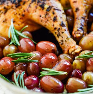 a pan with roasted grapes and a spatchcock chicken