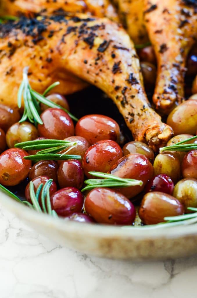 Roasted chicken with rosemary and grapes in a roasting pan