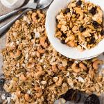 white bowl of granola surrounded by granola and spoons